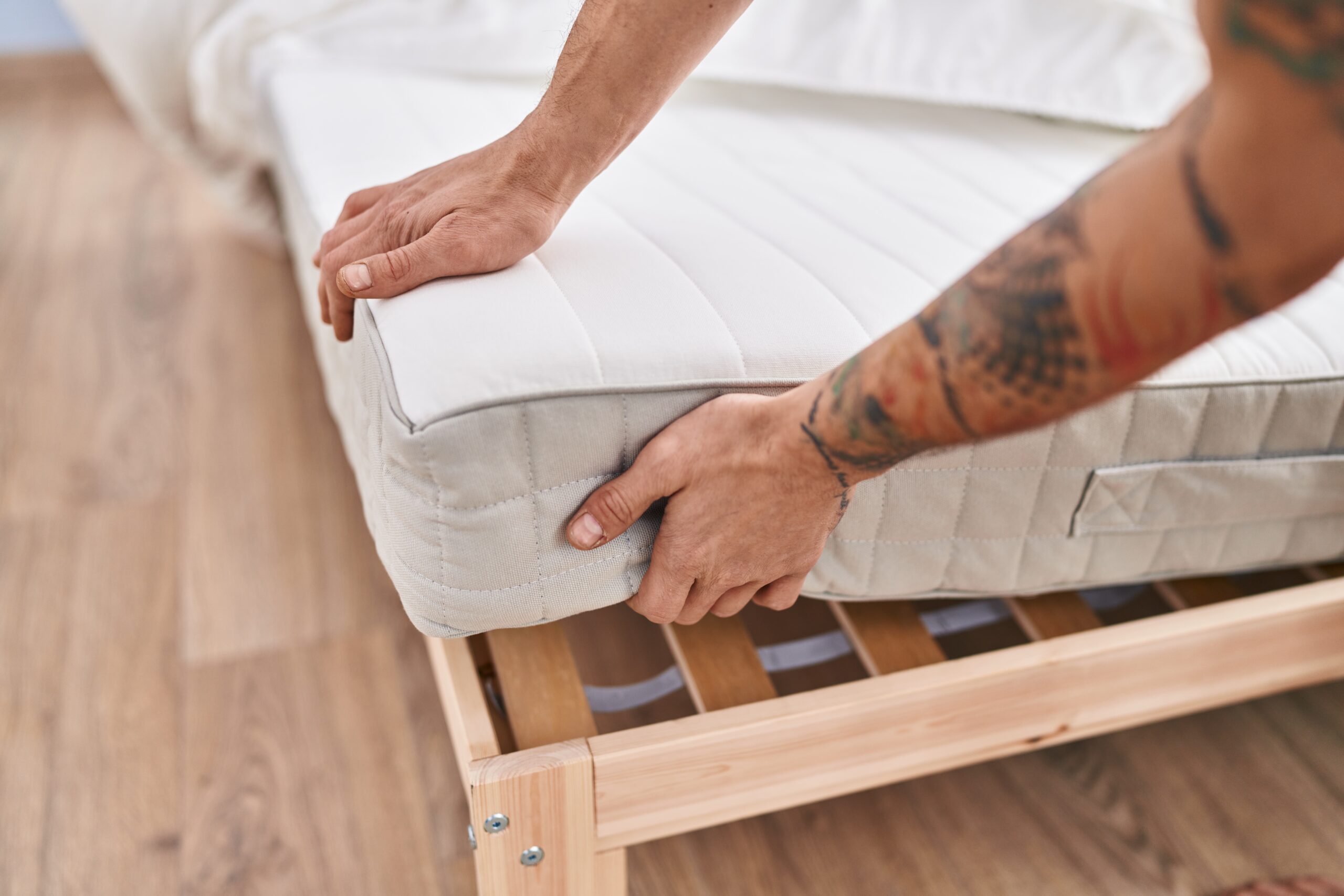 Lebonsommeil-Jeune homme tenant un matelas dans une chambre à coucher